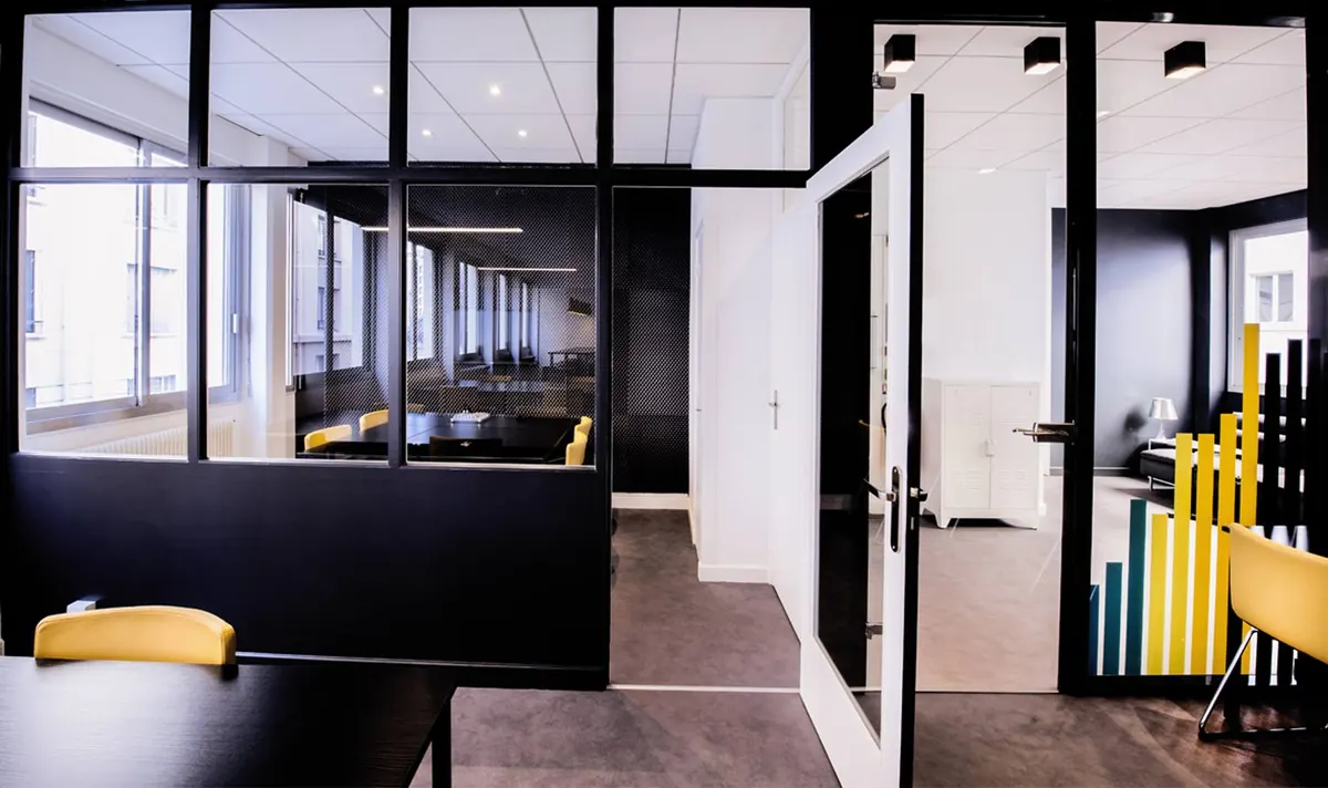 La salle de réunion vitrée, décorée de bandes jaunes et bleues.